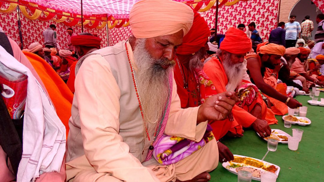 Haryana, India – February 11, 2018: Group of Indian sadhu or religious saint sitting together in a row & having lunch together during religious event.